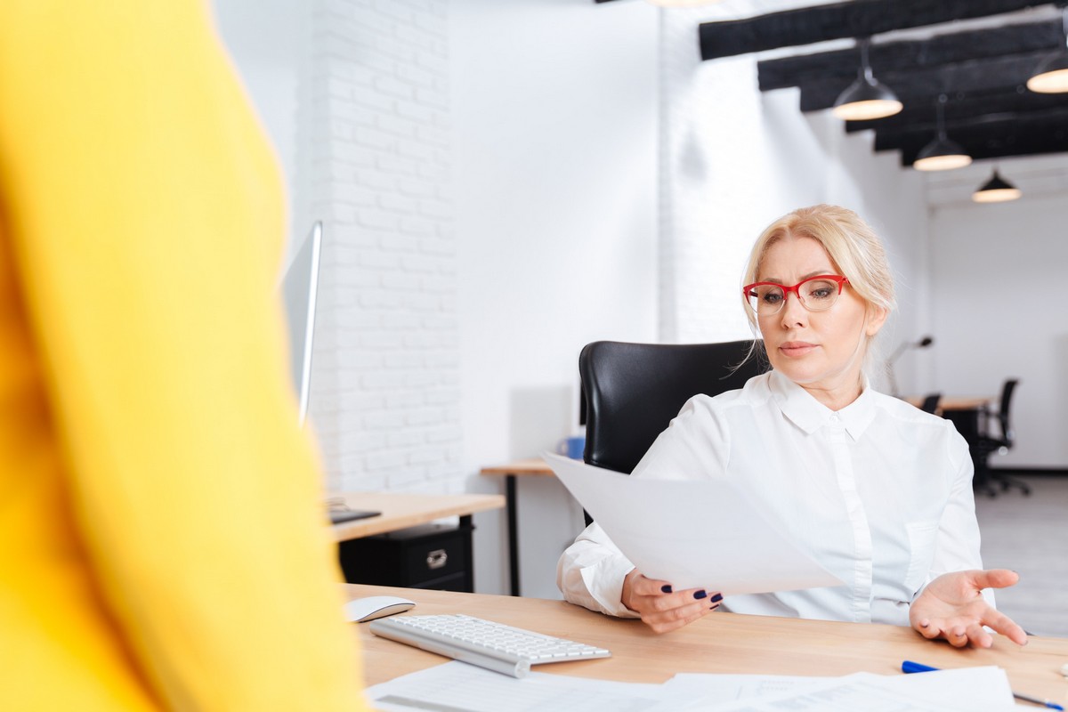 cheerful-beautiful-mature-businesswoman-interviewing-candidate-for-new-position-in-office